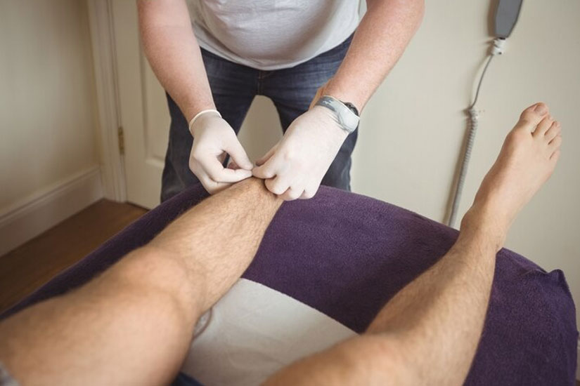 Professional therapist applying wax strip to a client's leg during a leg wax Perth salon session