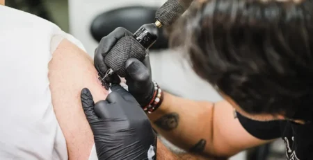 Best tattoo removal Perth – close-up of tattoo artist applying ink to a man's arm at a Perth grooming clinic
