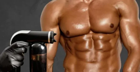 Spray tanning for men showing a muscular man receiving a professional full-body spray tan treatment
